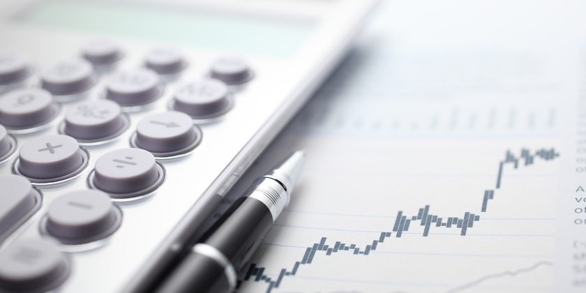 Calculator and ballpoint pen on stock market data chart